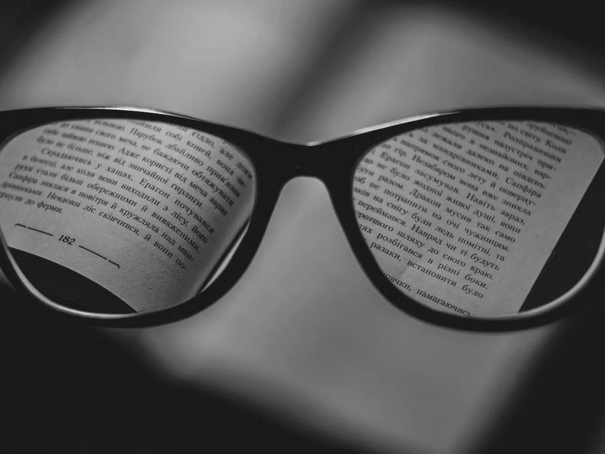 Referência de enquadramento: Texto lido através da lente. Plano macro, com o texto nítido no centro e o entorno fora de foco — é a única forma de mostrar campo de visão em foto parada.